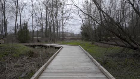 Camera-push-on-wooden-walkway-over-swamp-in-slow-motion-on-an-overcast-day-in-winter