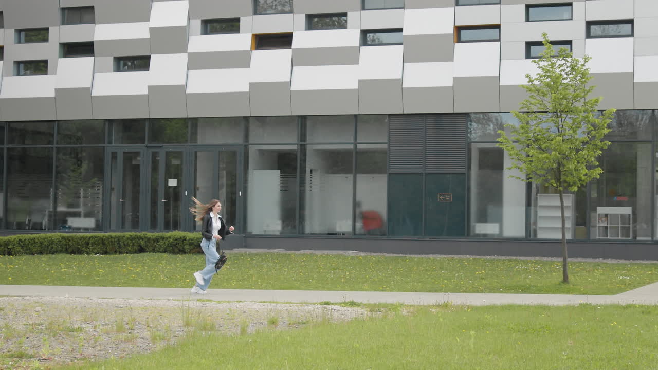joven estudiante adolescente en una chaqueta de cuero con una mochila elegante vestido corre cerca de un moderno