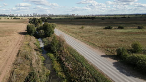 Aerial view of a road through a rural landscape with a city in the distance