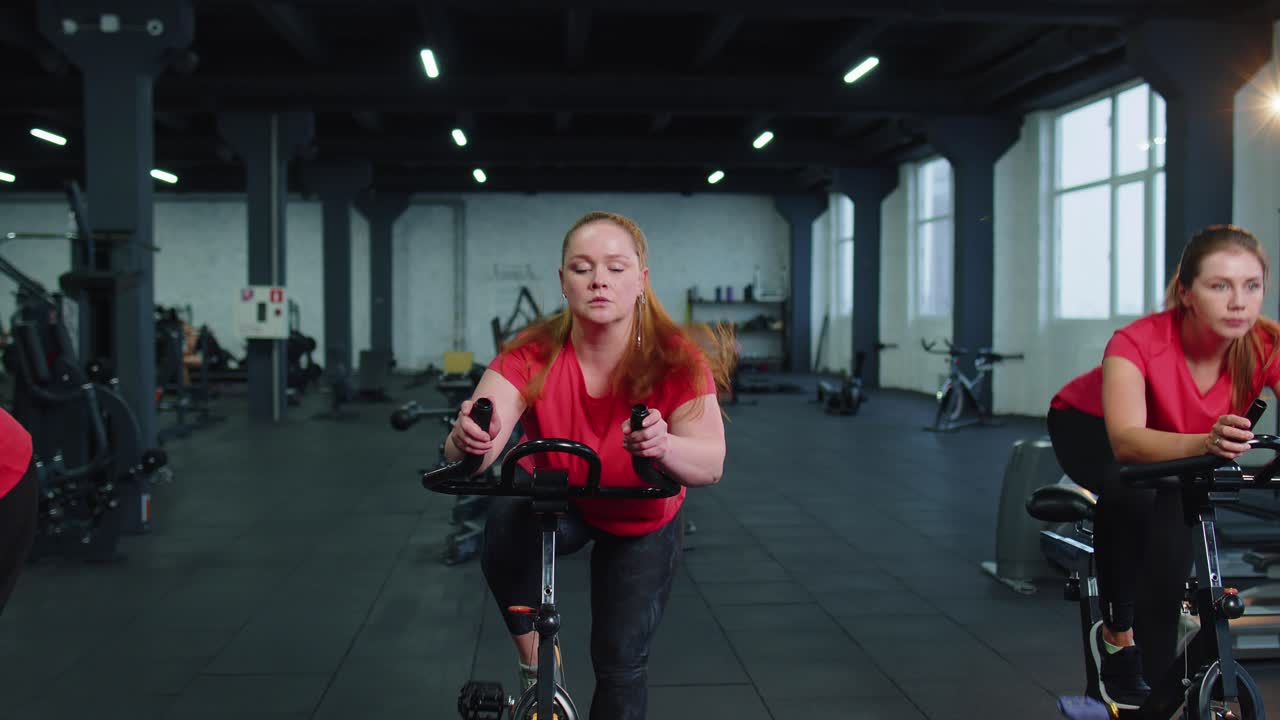 Un gruppo di ragazze esegue un allenamento aerobico, un allenamento cardio su simulatori di bicicletta, un addestramento ciclabile.
