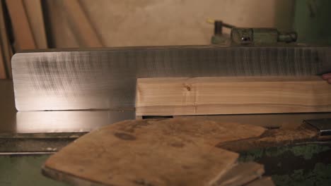 Man-In-Overalls-Polish-And-Align-Boards-With-Electric-Saw,-In-A-Carpentry-Workshop