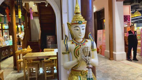 people shopping near a decorative buddha statue