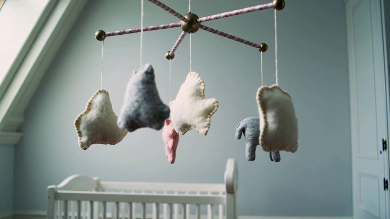 Rotating handcrafted baby mobile revealing nursery as camera pulls back, showing crib and skylight
