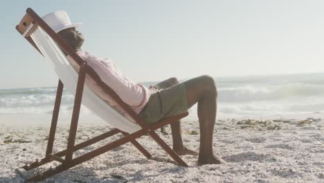 senior african american man lying on sunbed on sunny beach