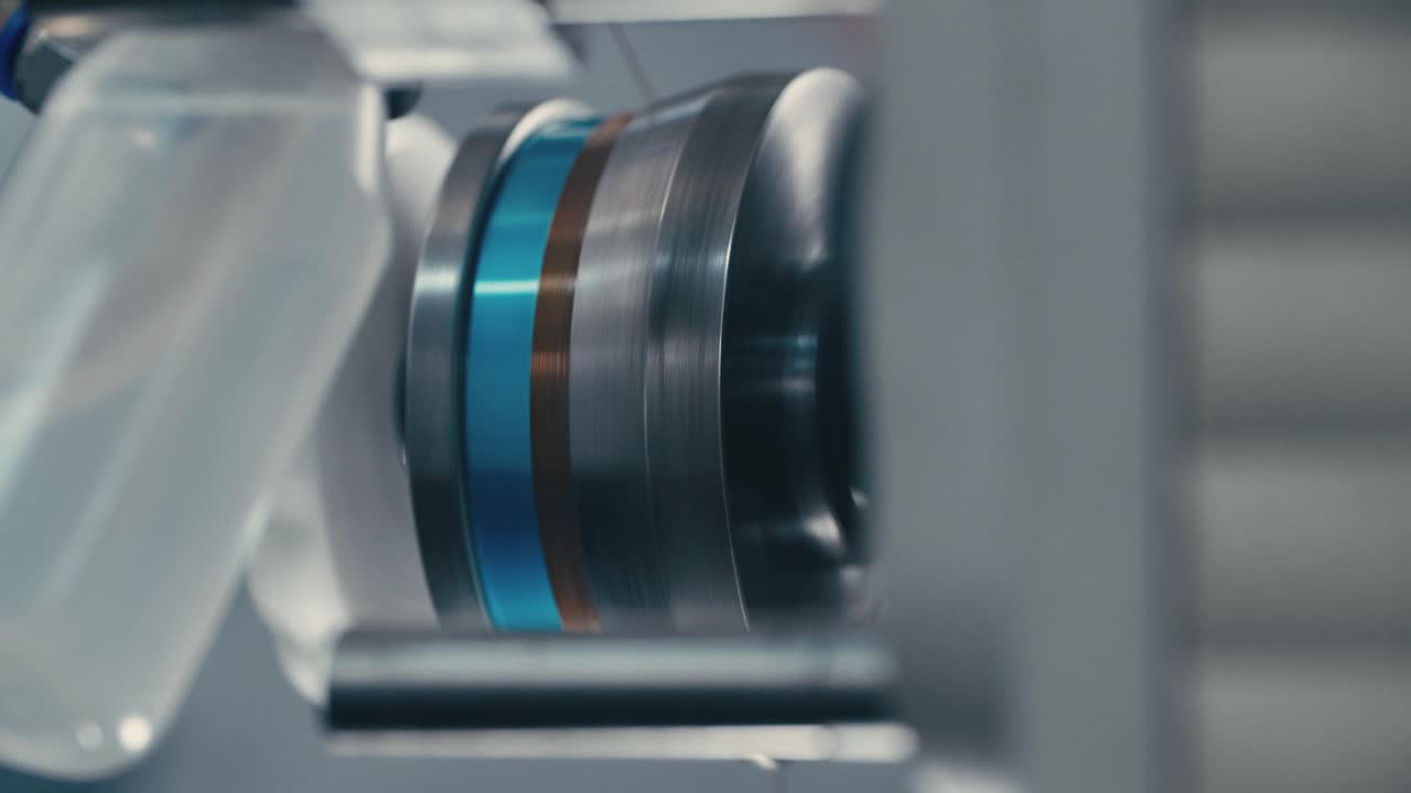 Industrial coil winder spinning wire around a core in slow motion, representing precision and technological excellence
