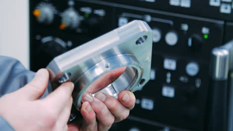 worker holding steel part in hands. workerman checking metal part for defects