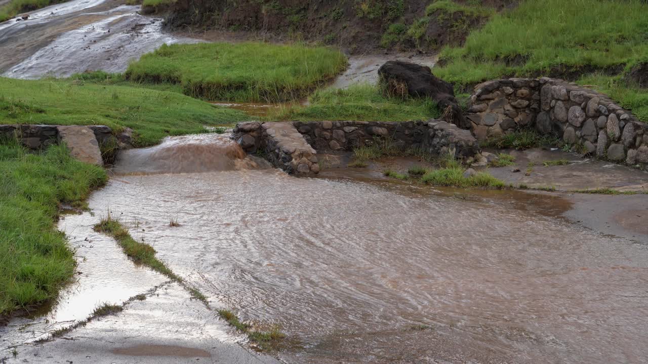 inundaciones de agua de río fangosa a través de una alcantarilla de hormigón en una carretera rural
