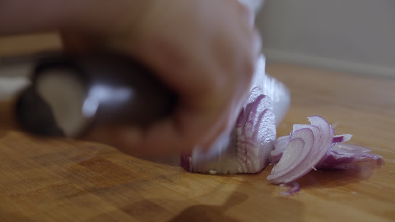 Slicing onion with sharp knife on a cut board