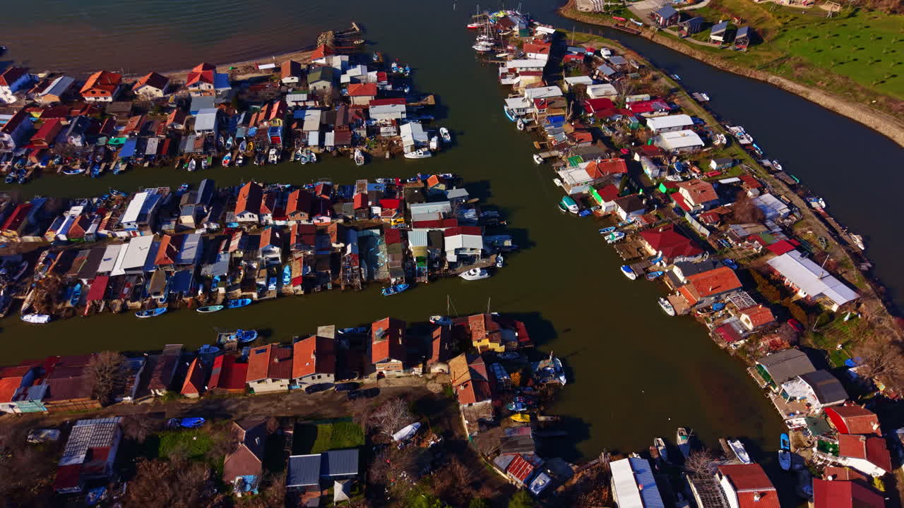 Blick auf Häuser und Boote entlang eines Flusses mit engen Kanälen in einem Uferbereich tagsüber.