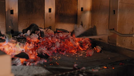 raking coals into a wood fired grill