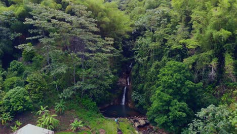 Epic-aerial-waterfall-views-in-the-rainforest-of-Grenada-with-houses-in-the-foreground-and-mountains-in-the-background