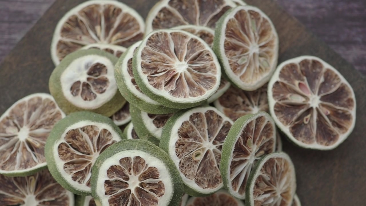 Pila di fette di lime verde essiccate su uno sfondo di legno