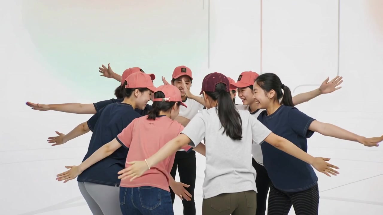 On cue raising women forming huddle for team bonding in studio, wearing baseball caps and tees