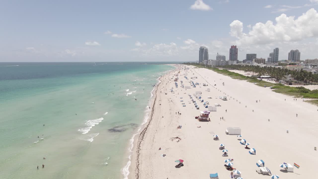 Sobrevuelo aéreo bajo de personas disfrutando de la soleada y arenosa South Beach Miami