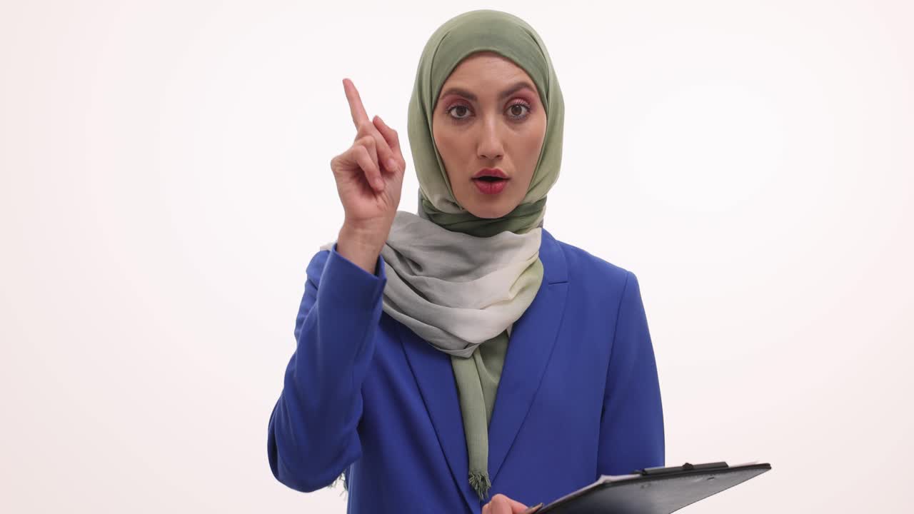 Thoughtful Muslim businesswoman in hijab holding a clipboard