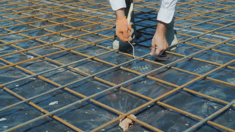 el trabajador conecta hábilmente las barras de la armadura con preparación de alambre para verter hormigón i