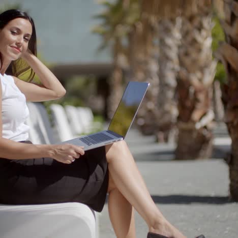 Attractive-woman-sitting-on-a-bench-with-a-laptop