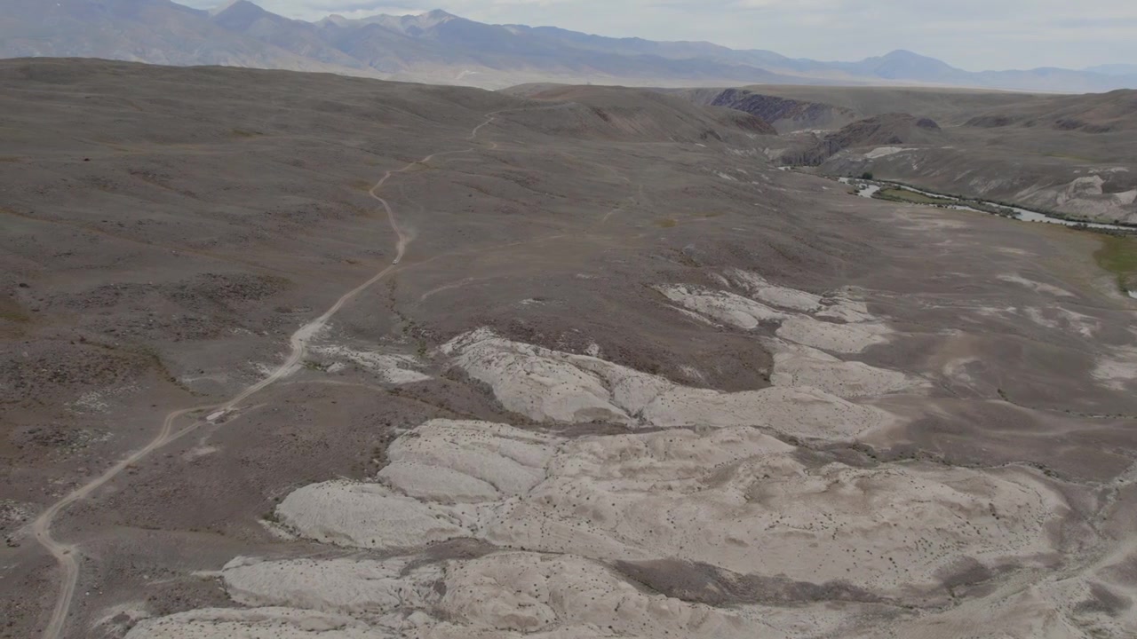 Imágenes de dron del Paisaje Lunar en Altai, Rusia, mostrando colinas de arcilla estériles, barrancos secos y senderos sinuosos bajo un cielo nublado, un escenario de naturaleza salvaje remota