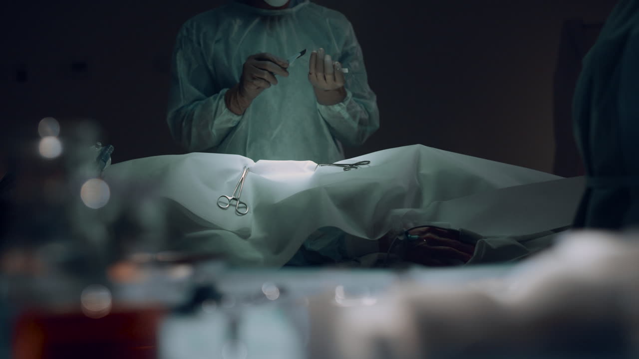 전문 외과 의사가 어두운 수술실에서 수술하기 전에 절개를 하고 있습니다.