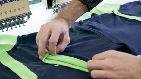 primer plano de la mano del hombre en una fábrica de costura comprobando camisetas