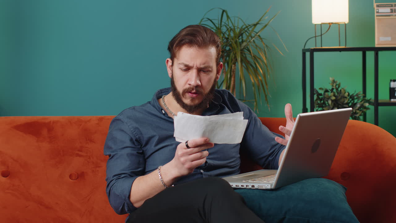 Stressed lebanese man looking at unpaid bank debt loan doing paperwork planning budget throws bills