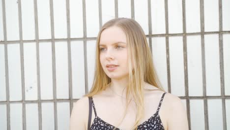 handheld static shot of young blonde woman standing in front of a white, tiles wall in sheffield, england