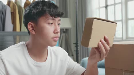 close up of asian man online seller look at the package and write in the notebook while selling clothes at home