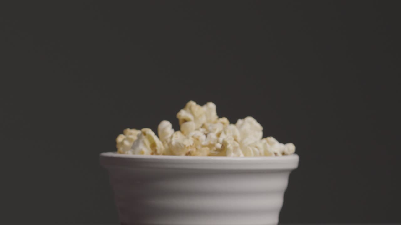 Sliding Shot Approaching a Bowl of Popcorn as Hand Takes Some