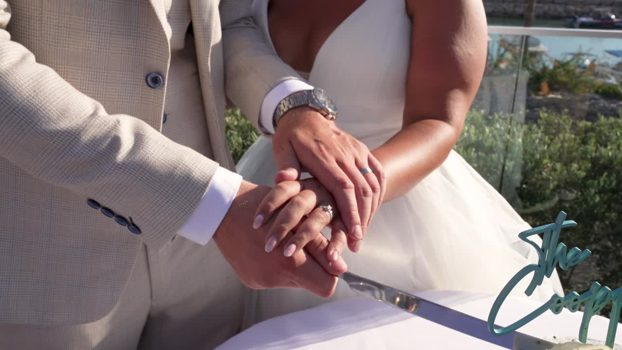 A couple joyfully cuts their wedding cake together, surrounded by nature and the warm glow of sunlight. Friends and family cheer as they celebrate their special day