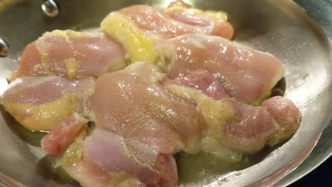 cooking chicken thighs in a stainless steel pan