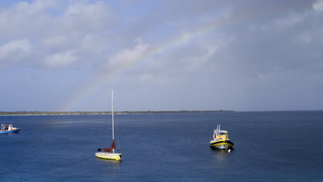 boats with rainbow in ocean near coast of bonaire, the caribbean, the antilles