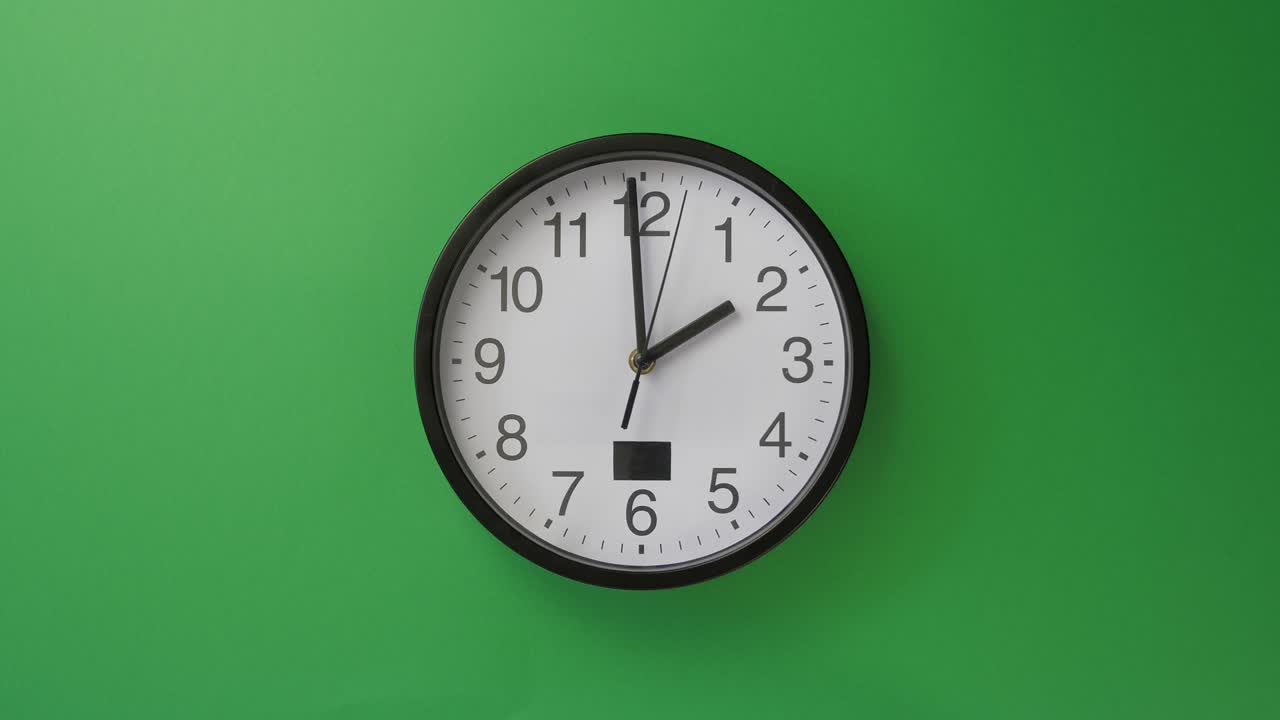 Orologio da ufficio bianco singolo appeso su sfondo verde.