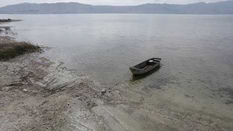 Video-with-a-drone-on-Lake-Skadar-in-Albania,-on-an-old-wooden-boat-in-the-foreground,-surpassing-it-in-different-planes-at-water-level