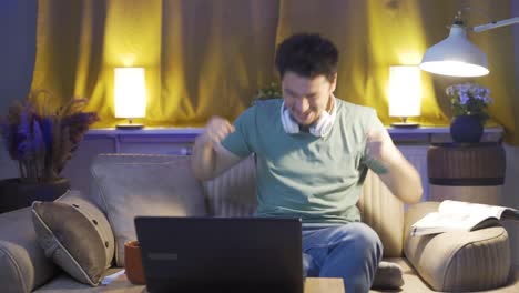 un estudiante varón que está feliz de que sus resultados de los exámenes son buenos. en casa por la noche.