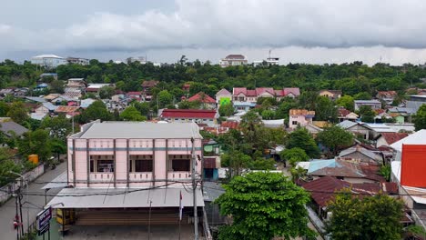 landscape view of residential houses, shops and businesses nestled amongst green trees in kupang, east nusa tenggara, indonesia