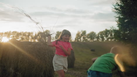 smiling siblings playfully throw hay on each other while bathed in warm golden sunlight, the sun rays create a magical atmosphere in the serene countryside