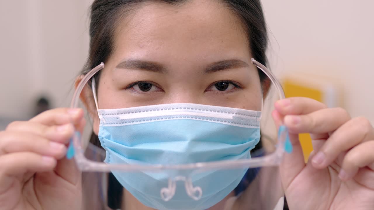 안경과 눈을 보호하기 위해 얼굴 주위에 마스크를 둥글게 하여 안면 보호대를 착용하고 있는 아시아 젊은 여성의 초상화, 슬로우 모션 장면