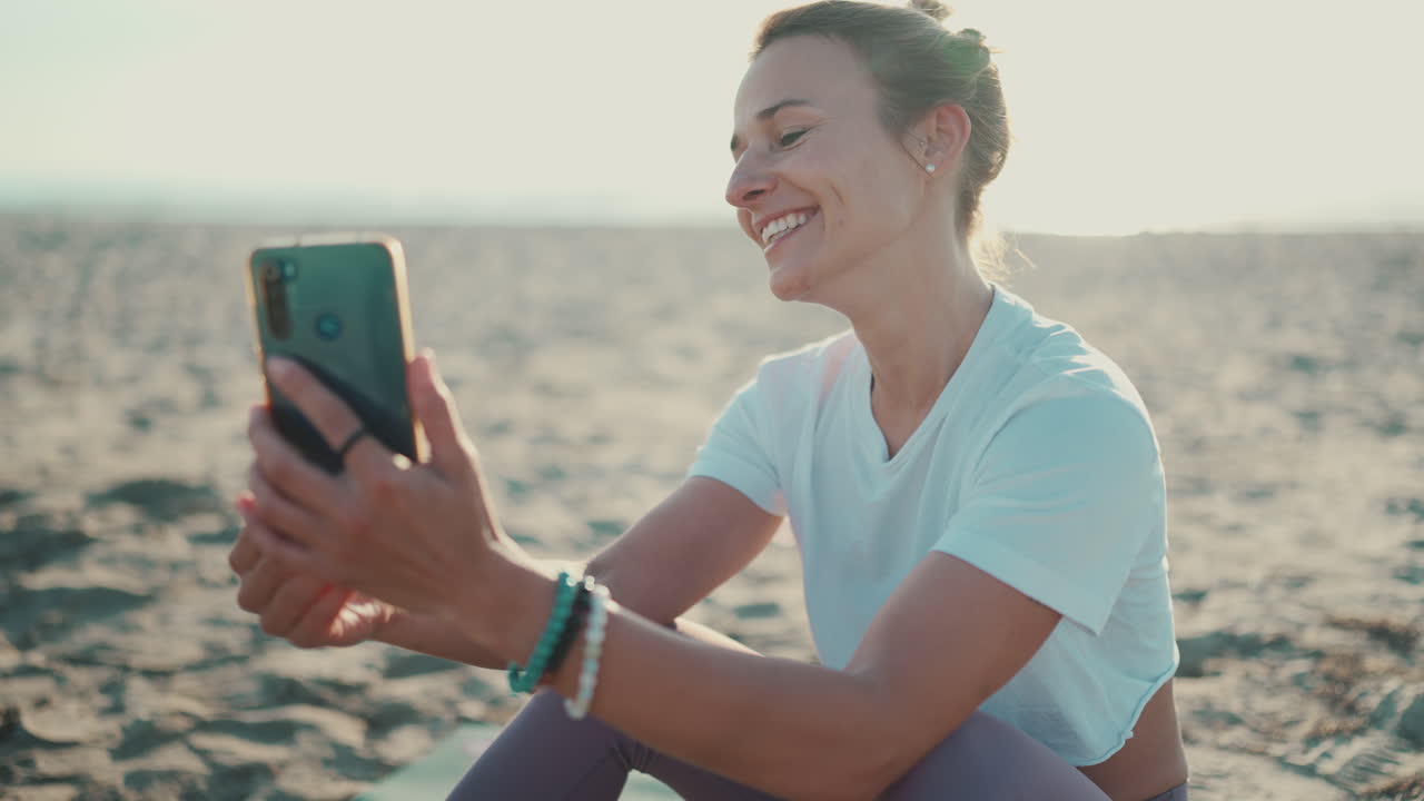 una mujer joven haciendo una llamada de video en la playa.