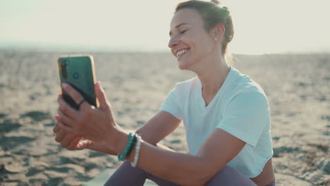 una mujer joven haciendo una llamada de video en la playa.