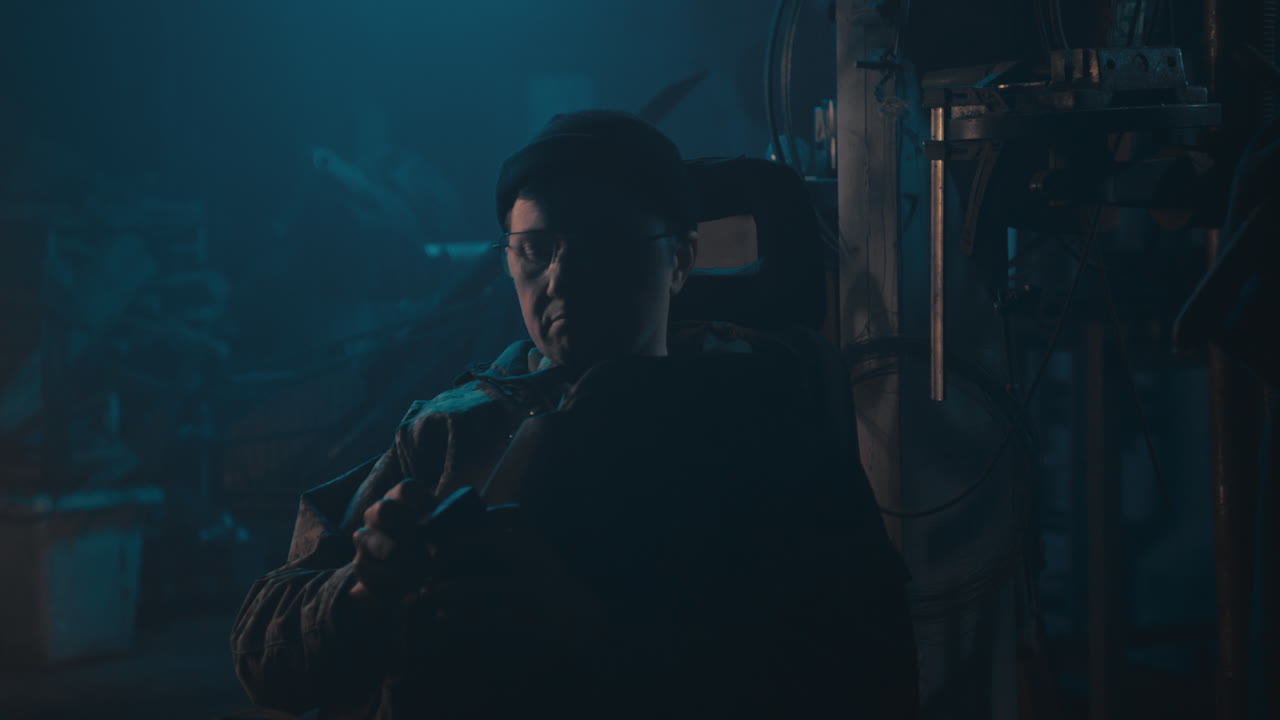 Mysterious man in the workshop at night smokes a cigarette