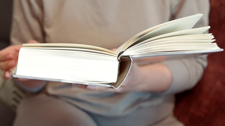 Primo piano di una donna che legge un libro sul divano di casa