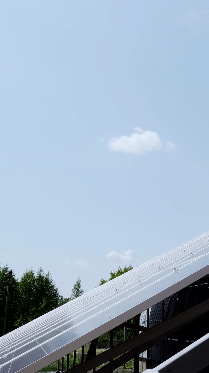 The construction of a large solar panel on a background of green forest and sky. Alternative energy. Vertical video