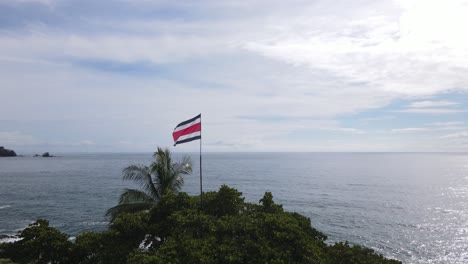 the flag of costa rica sits upon a mountain with a view of the sea behind