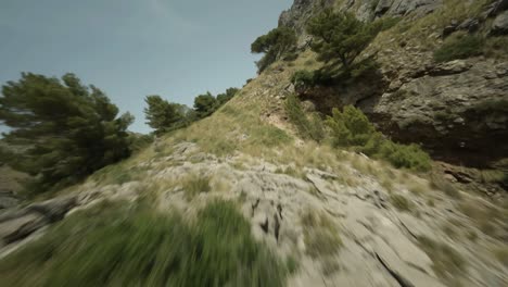 FPV-drone-shot-over-amazing-rocky-cliff-along-the-beachside-with-beautiful-turquoise-colored-sea-water-on-a-sunny-day