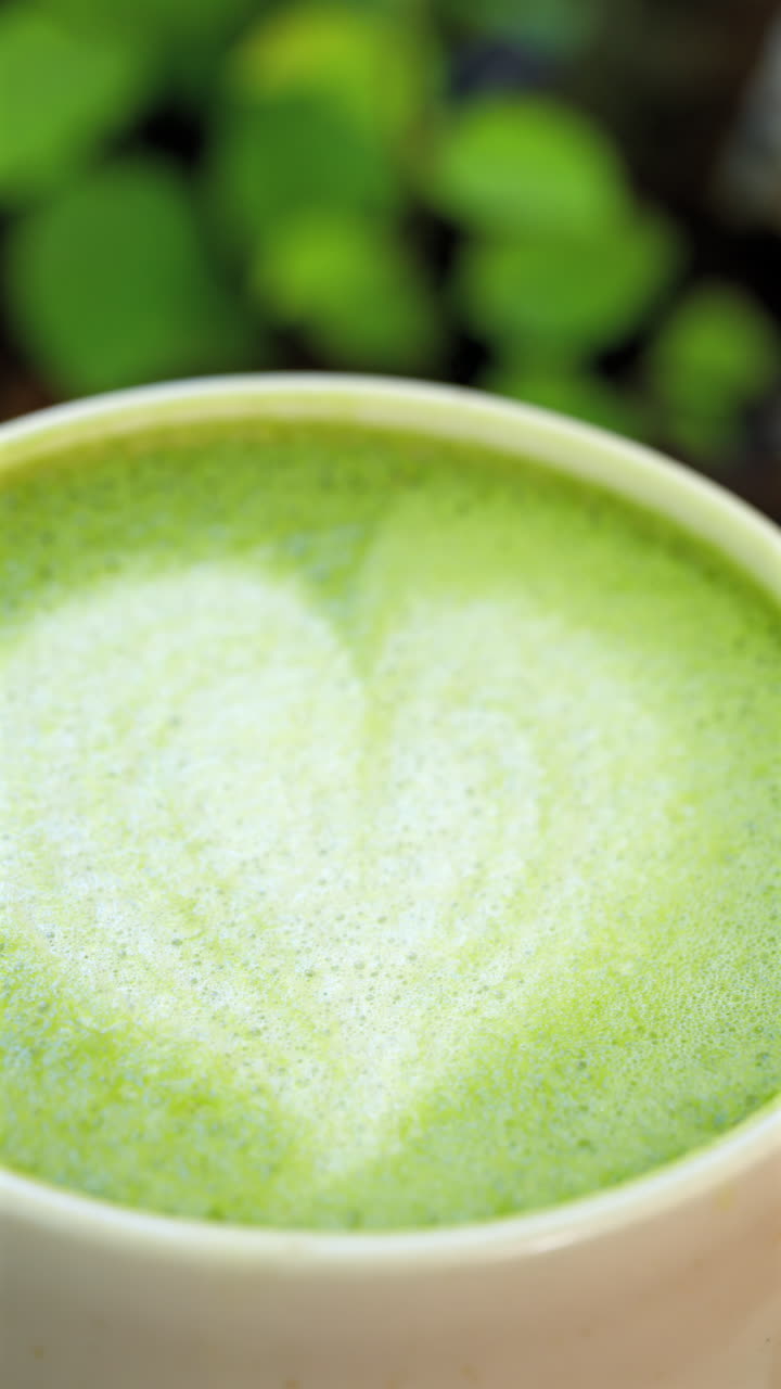 Close up of a heart latte art on a matcha latte. Vertical