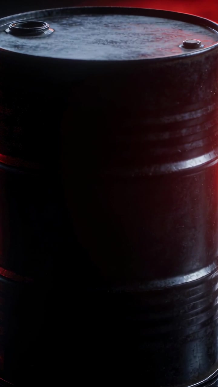 Vidéo verticale : Une lumière rouge-orange pulsante éclaire un fût noir, révélant une lueur et deux bouchons de bonde en stockage.
