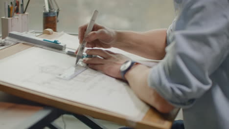 engineer works in a bright office with a large window concentrates and draws blueprints. workplace of an architect or designer: loft style minimalistic interior drawings