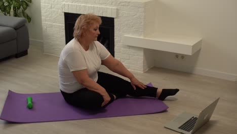 Home-Sport.-Active-Senior-Woman-Doing-Warming-Stretching-Exercises-In-Front-Of-Laptop,-Training-With-Online-Tutorials
