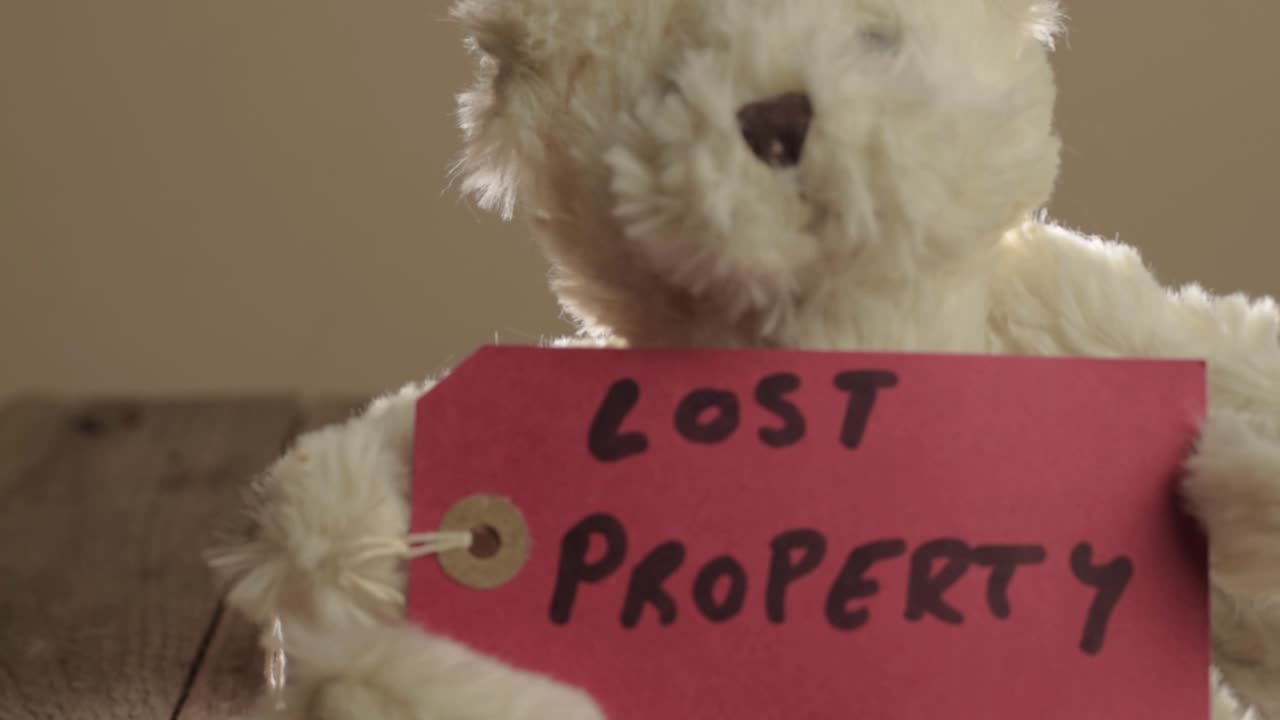 분실물을 표시하는 빨간색 라벨이 붙은 테디 베어가 가까이 있습니다.