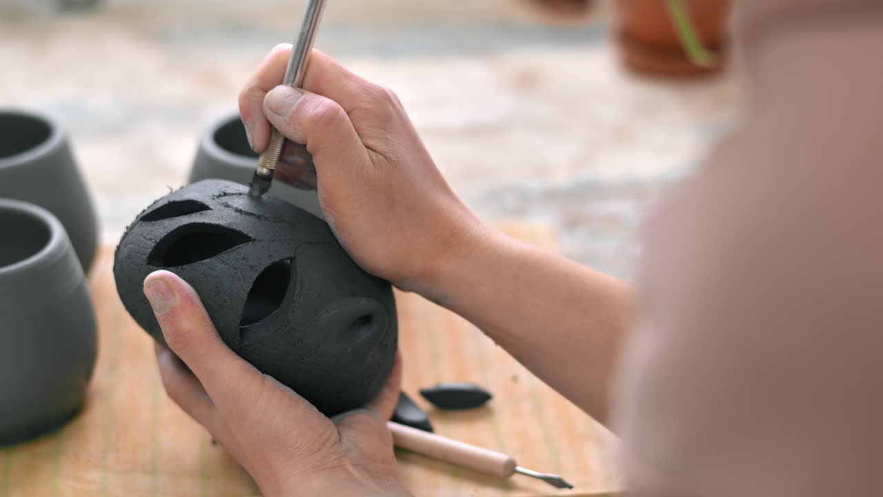 The master of sculpting pottery working in a studio. Cuts holes in fresh pottery
